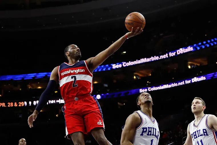 Washington Wizards' John Wall (2) goes up for a shot against Philadelphia 76ers' Ish Smith (1) and Nik Stauskas (11) during the first half of an NBA basketball game, Thursday, March 17, 2016, in Philadelphia.