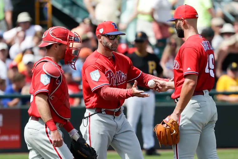 Phillies pitcher Jake Arrieta hands the baseball to Manager Gabe Kapler with catcher Andrew Knapp before Arrieta left the game in the fourth-inning against the Pittsburgh Pirates in a spring training game on Thursday, March 14, 2019 at LECOM Park in Bradenton, FL.