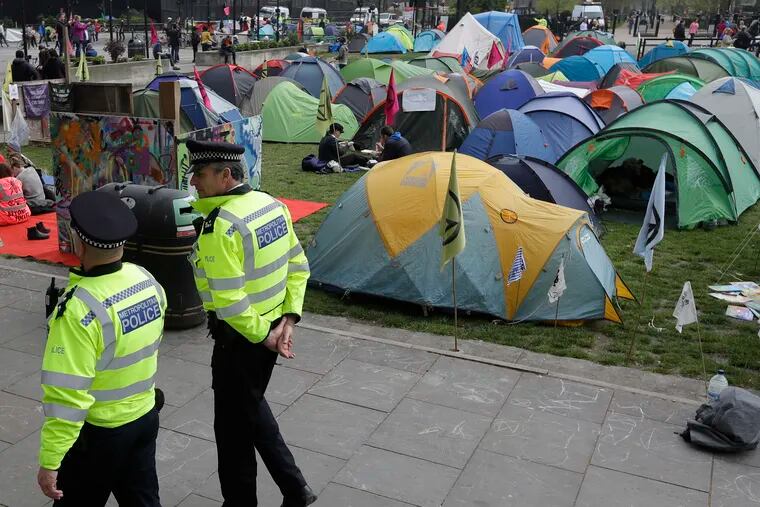 Police officers patrol past a village of tents during a climate protest at Marble Arch in London, Tuesday, April 16, 2019. The group Extinction Rebellion is calling for a week of civil disobedience against what it says is the failure to tackle the causes of climate change. (AP Photo/Kirsty Wigglesworth)