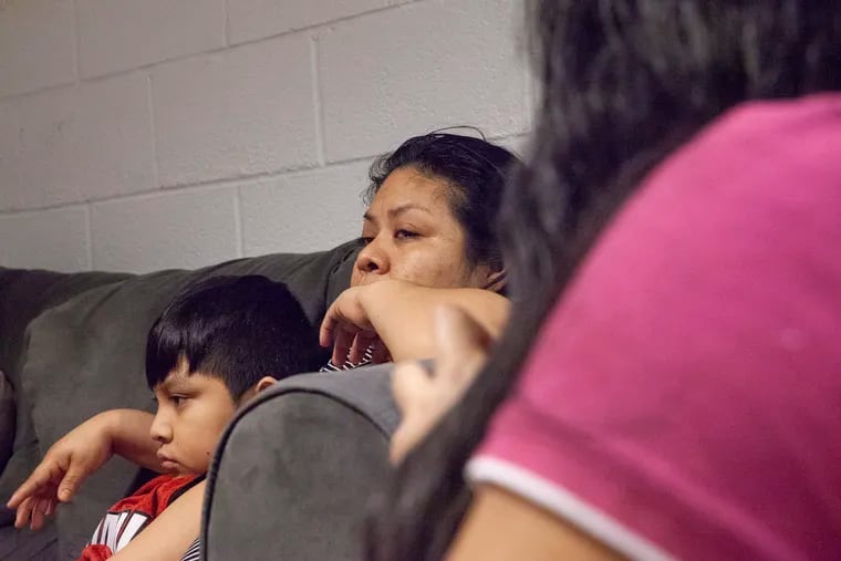 Carmela Hernandez, right, tears up during an interview, sitting beside her son Edwin inside the basement of the Church of the Advocate.
