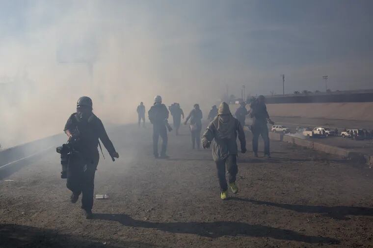 Migrants run from tear gas launched by U.S. agents, amid photojournalists covering the Mexico-U.S. border, after a group of migrants got past Mexican police at the Chaparral crossing in Tijuana, Mexico, Sunday, Nov. 25, 2018.