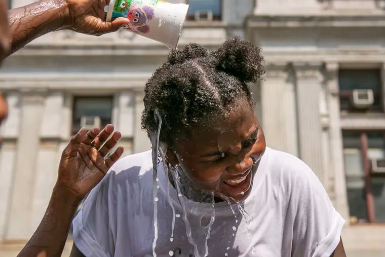 Savannah Bethea, 10, of West Philly, reacts to having water poured on her while she plays in the fountains at Dilworth Park on Friday, July 19, 2019. Southeastern PA is currently under an excessive heat warning, with temperatures reaching middle 90s on Friday and upper 90s to 100 over the weekend.