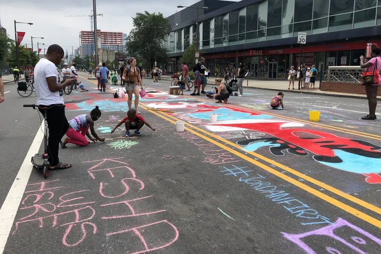 Mural Arts staff artist James Burns creates a street mural with chalk spray paint on Broad Street and Cecil B. Moore Avenue at Philly Free Streets on Saturday, August 11, 2018.
