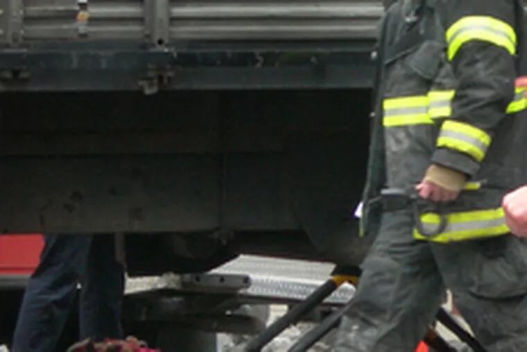 Firefighter walks past the body of woman who was struck and killed by a truck at Broad and Arch streets.