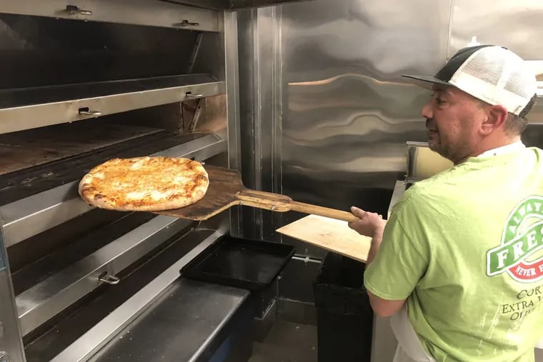 Danny DiGiampietro loads a pizza into the oven at Angelo's Pizza in South Philadelphia.