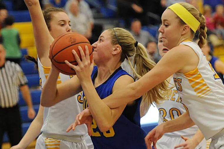 Downingtowng East Paige Warfel (center) drives to the basket against
Downingtown West Megan Camden and Heather Camden. (Photo by Bradley C Bower)