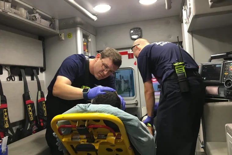 David Sullivan (left) a paramedic, and Brent Helvig, an EMT, treat a man suspected of overdosing on heroin in June 2017.