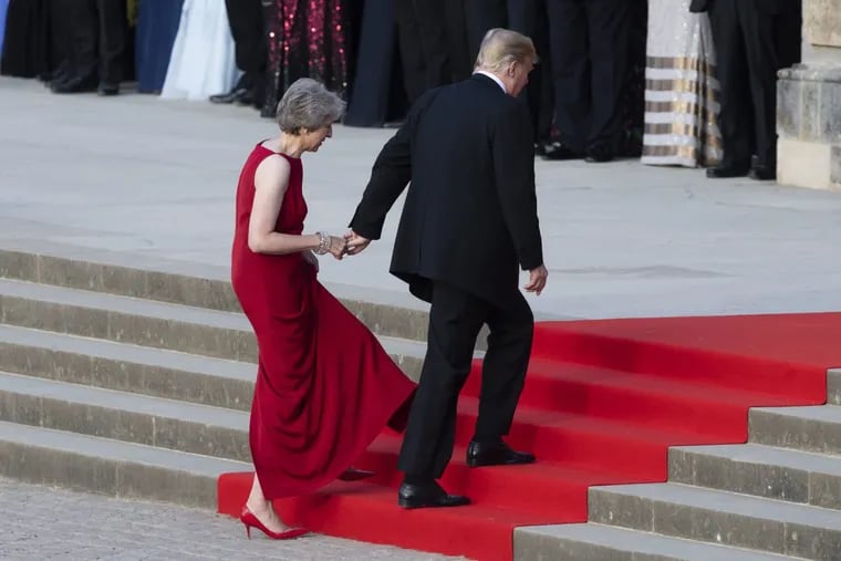 British Prime Minister Theresa May takes the hand of President Trump as they walk up red-carpeted steps to enter Blenheim Palace for a black tie dinner in Blenheim, England, Thursday, July 12, 2018.