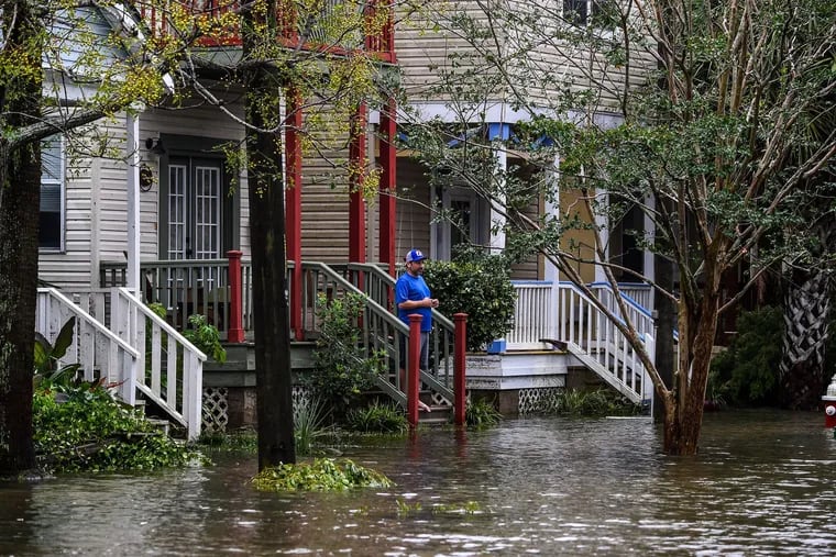 A man, standing outside of his home, watches a street flooded by Hurricane Sally in Pensacola, Fla., last month.