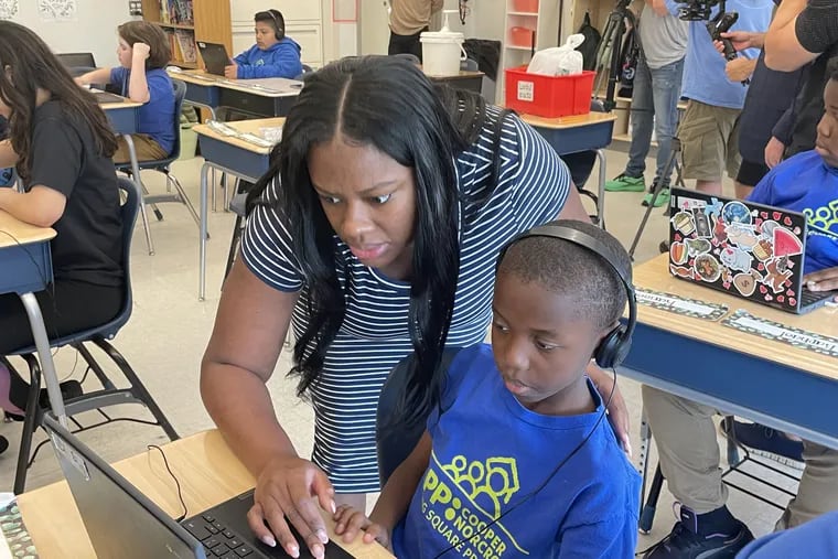 Erica Nelms, an elementary school teacher at KIPP Lanning Square Primary in Camden, helps a student moments before she received a $5,000 RISE award from the Camden Education Fund. She was cited for improving students' reading scores.