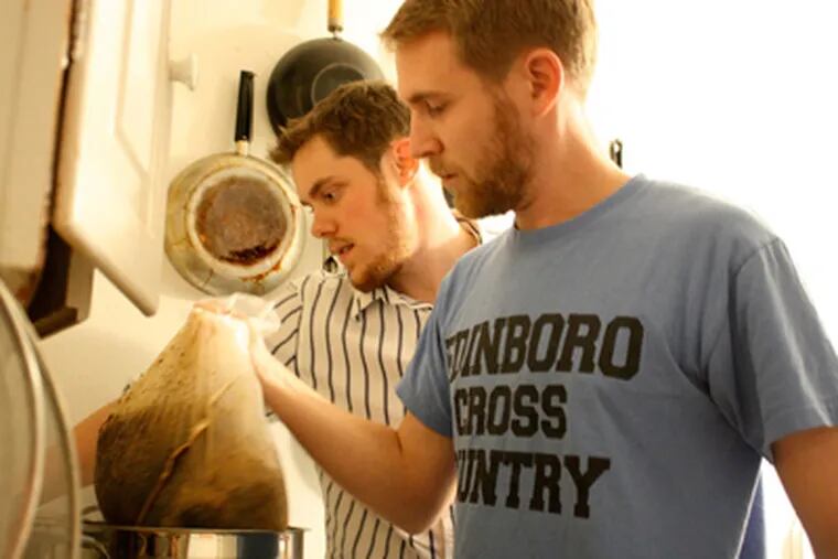 Eric Woods (left) and his Narbrew partner, Jeremy Boehm, work together to pull the grains from the pot while brewing a batch of their Santa Java Stout.