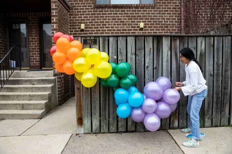 Jace Florescio, balloon stylist and founder of Florescio Events, attaches a rainbow balloon garland to a home in Fairmount in Philadelphia, Pa. on Monday, March 30, 2020. After reading a story about rainbow hunts for kids Florescio put a rainbow balloon garland on the front of her Fairmount home. Neighbors noticed and began putting in orders for their own. Since then she's installed more than 100 garlands at homes around her neighborhood.
