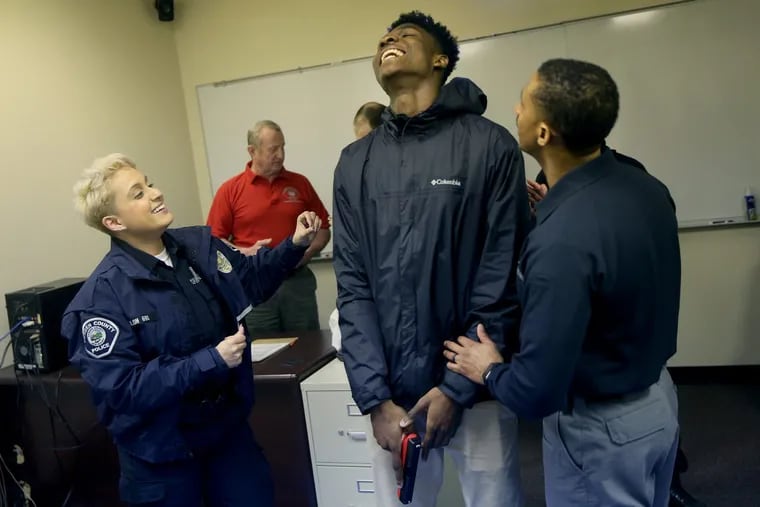 Officer Danielle Colon, left, and Sgt. Raphael Thornton, right, prepare Woodrow Wilson High School junior Stanley King, 17, to try a use-of-force simulator at the Camden County Police Academy in Blackwood, N.J., on Friday, March 2, 2018. Camden County police and Woodrow Wilson students are participating in a youth-police engagement program facilitated by the New York University School of Law’s Policing Project.