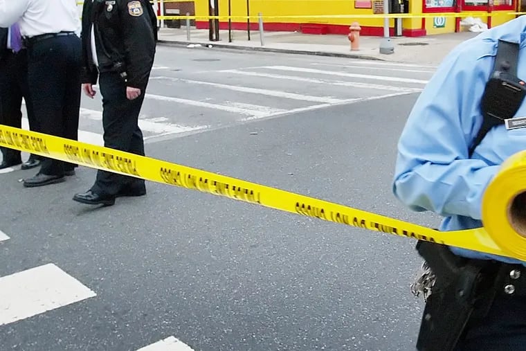Philadelphia police run crime scene tape.