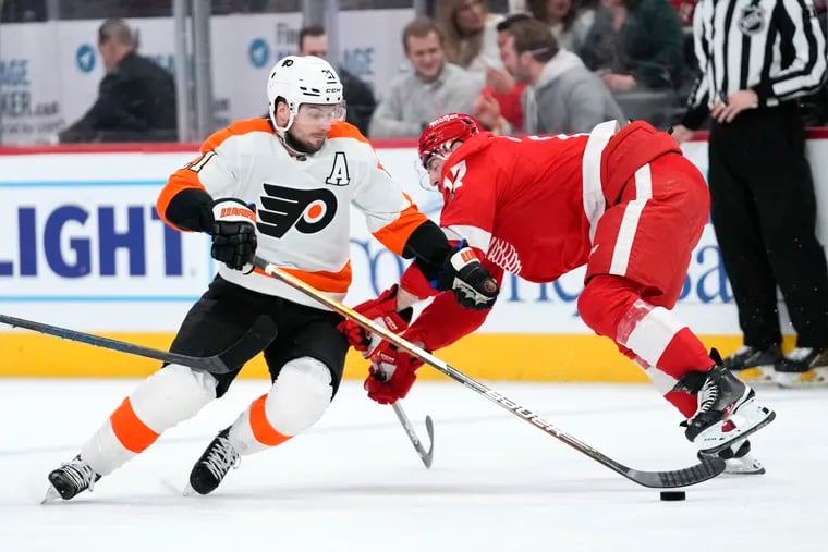 Flyers center Scott Laughton (center) battles for the puck in a game against the Detroit Red Wings on Saturday.