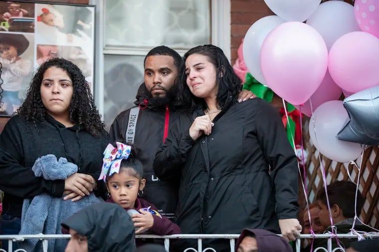 Nikolai Rivera (center) and Joan Pagan (right), the father and mother of Nikolette Rivera, the 2-year-old girl who was was fatally shot on Sunday, stand on their porch during the candlelight vigil in memory of their daughter.