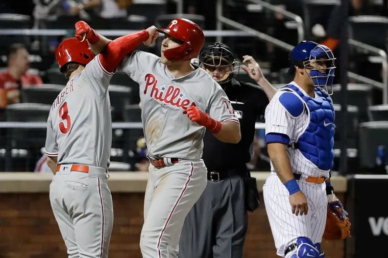 New York Mets catcher Wilson Ramos, right, looks away as Philadelphia Phillies' Bryce Harper, left, celebrates with Rhys Hoskins, center, after Hoskins hit a two-run home run during the ninth inning of a baseball game, Wednesday, April 24, 2019, in New York. (AP Photo/Frank Franklin II)