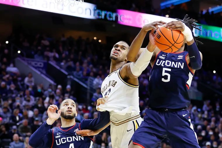 Villanova forward Eric Dixon reaches for the ball against Connecticut forward Isaiah Whaley (right) as Dixon gets his jersey grabbed by guard Connecticut guard Tyrese Martin during the second half on Saturday, February 5, 2022 in Philadelphia.
