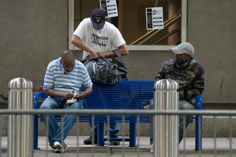A group of men gather their belongings on a bench outside Terminal A at the airport as people who have been staying at the airport are relocated, on Tuesday, May 26, 2020.