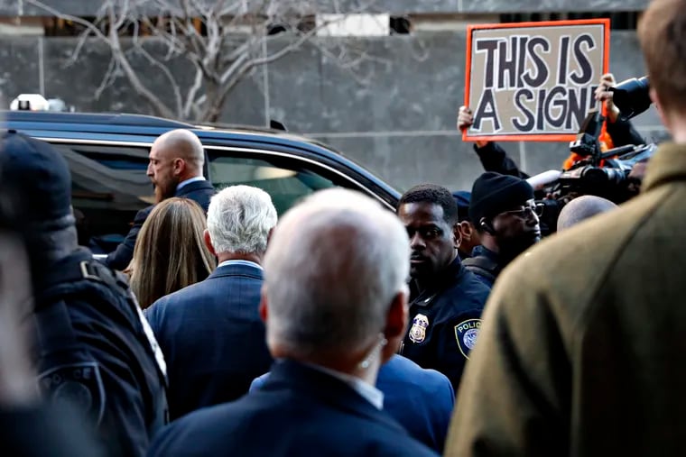 Former campaign adviser for President Donald Trump, Roger Stone, center left, walks to his vehicle as he leaves federal court Thursday, Feb. 21, 2019, in Washington, between members of the media, security, and protesters. A judge has imposed a full gag order on Trump confidant Roger Stone after he posted a photo on Instagram of the judge with what appeared to be crosshairs of a gun. (AP Photo/Jacquelyn Martin)