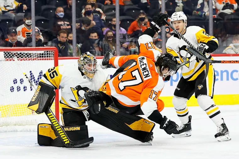 Flyers center Zack MacEwen falls over Penguins goaltender Tristan Jarry with defenseman Chad Ruhwedel looking on.