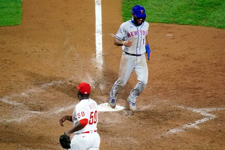 The Mets' Amed Rosario (1) scores the game-winning run Wednesday night as Phillies pitcher Hector Neris watches.