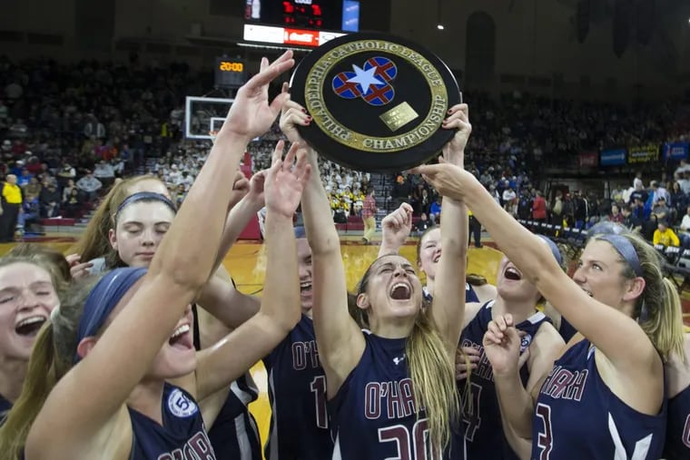 Hannah Nihill (center) of Cardinal O’Hara raises the Catholic League trophy after their 35-30 victory over Archbishop Wood in the Girls’ Catholic League Championship Game at the Palestra on Feb. 27, 2017