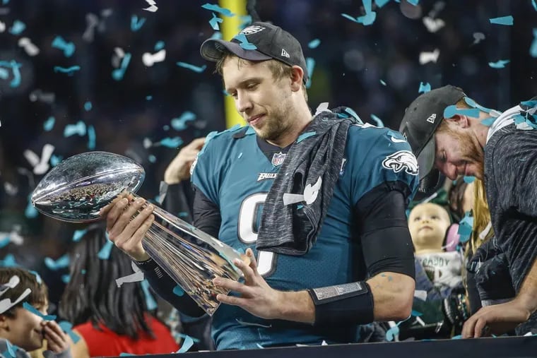 Eagle quarterback Nick Foles, left, taking a long look at the Lombardi Trophy on the victory stand as Carson Wentz, right, takes in the moment at the Super Bowl.