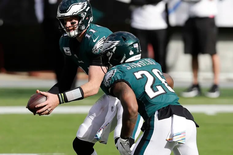 Eagles quarterback Carson Wentz holds the football with running back Miles Sanders against the Baltimore Ravens on Sunday, October 18, 2020.
