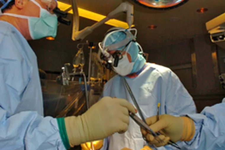 Dr. Francis P. Sutter, with surgical assistant Vincent Merola, harvests an artery for use in the bypass surgery.
