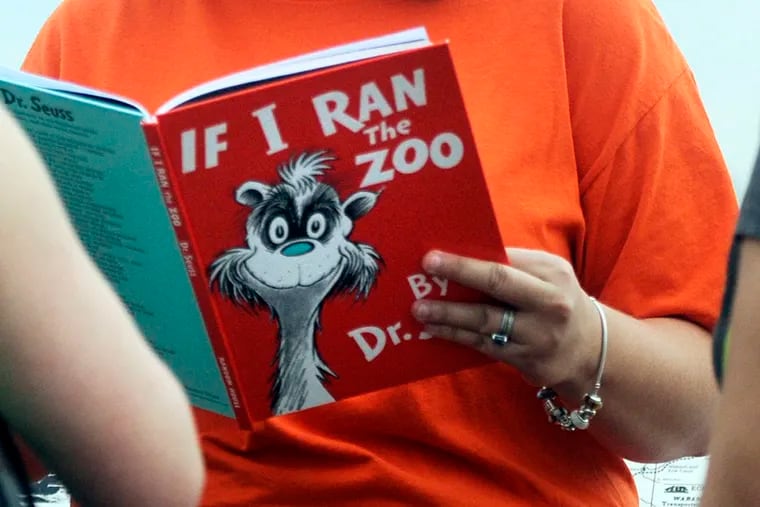 In this Sept. 24, 2013, file photo, Courtney Keating, education coordinator of The Literacy Center in Evansville, Ind., reads "If I Ran the Zoo," By Dr. Seuss, to passersby during an event to promote literacy. Dr. Seuss Enterprises, the business that preserves and protects the author and illustrator's legacy, announced on Tuesday, March 2, 2021, that it would cease publication of several children's titles including "And to Think That I Saw It on Mulberry Street" and "If I Ran the Zoo," because of insensitive and racist imagery.