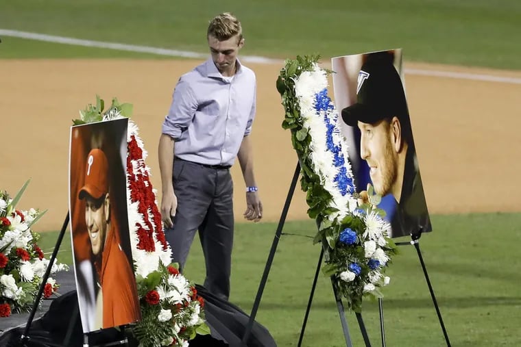 Braden Halladay, oldest son of late MLB pitcher Roy Halladay, looks at photograph of his father after a Celebration of Life for Roy Halladay at Spectrum Field in Clearwater, Fla., where the Halladay family lives.