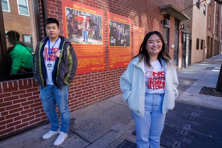 Wei Chen (left) and Cinthya Hioe of Asian Americans United stand in front of portraits of community members from the Chinatown community on display at Spring Street at N. 10th, as part of the "Our Chinatown" oral history project, Monday, Feb. 19, 2024.