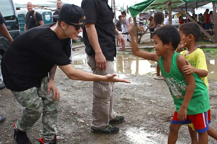Justin Bieber exchanges high-fives with children survivors of Typhoon Haiyan during his visit Tuesday to Tacloban, in the Philippines.