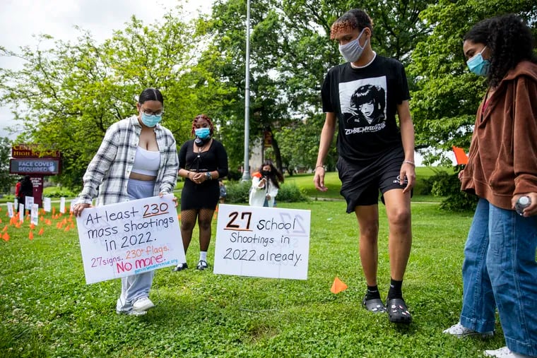 Central High sophomores Mahrin Begun, 16, (left), and Angelo Morales, 16, (right), set up signs sophomores and juniors made to draw attention to school shootings around the country. The signs and orange flags sit at the corner of Ogontz and Olney Avenues.