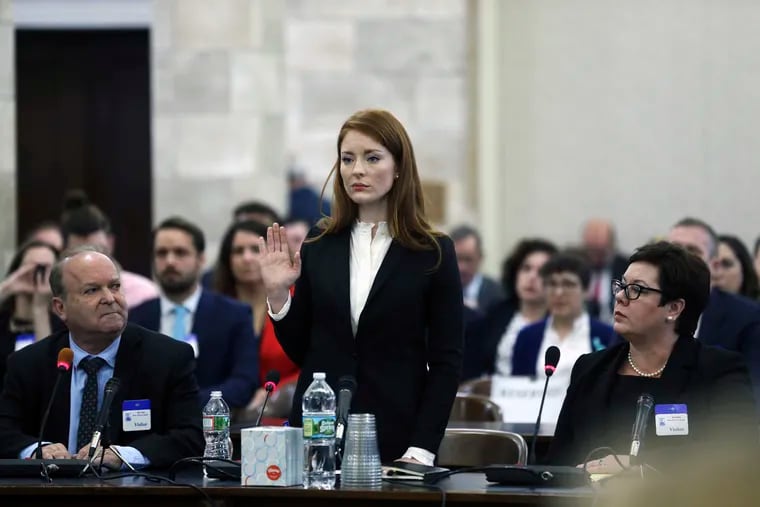 Katie Brennan, the chief of staff at the New Jersey Housing and Mortgage Finance Agency, raises her hand as she is sworn-in to testify before the Select Oversight Committee at the Statehouse, Tuesday, Dec. 4, 2018, in Trenton, N.J. Brennan, a top staffer at the state's housing agency came forward as sexual assault victim and has said too little was done about her complaints, which she reported to law enforcement.