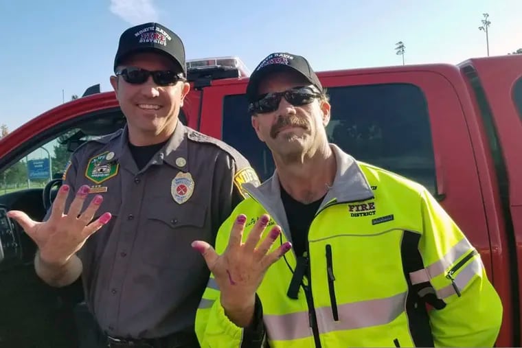 This Friday, Oct. 11, 2019, photo released by the North Davis Fire District shows Chief Allen Hadley, left, and Cpt. Kevin Lloyd In Clearfield, Utah. The two Utah firefighters are receiving praise after they found a creative way to keep a young girl calm at the scene of a car accident. North Davis Fire District Fire Chief Mark Becraft said the firefighters let a young girl paint their nails after she and her mother were in a car accident Saturday. Chief Hadley and Cpt. Lloyd checked on the crying and screaming girl while medics evaluated her mother. Nobody was seriously injured.