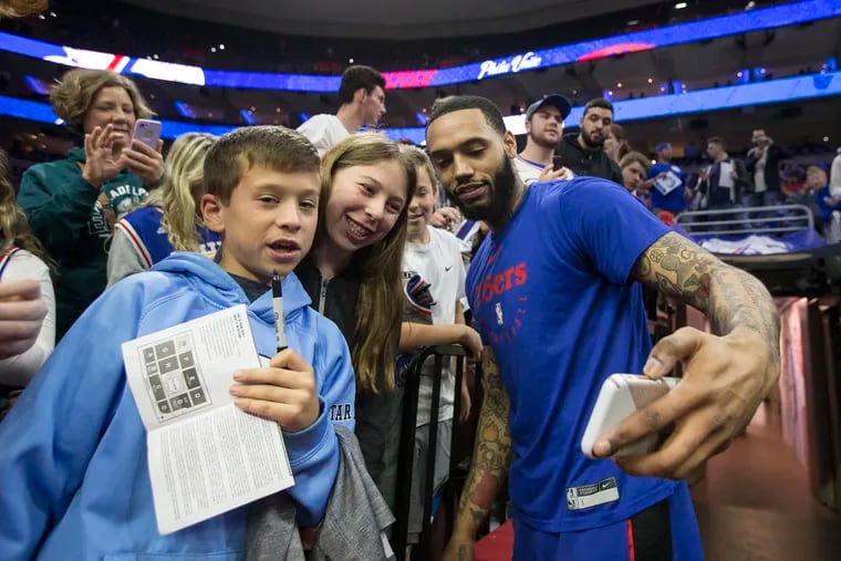 Mike Scott (right) poses with fans after a warm-up during the NBA playoffs.