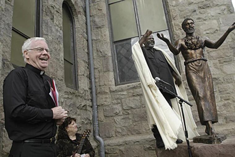 At Sacred Heart Church in Camden, Father Michael Doyle, left, grins as Willie Barnes unveils the statue of a black Jesus that was created by Father Leonard Carrieri. (April Saul / Inquirer)