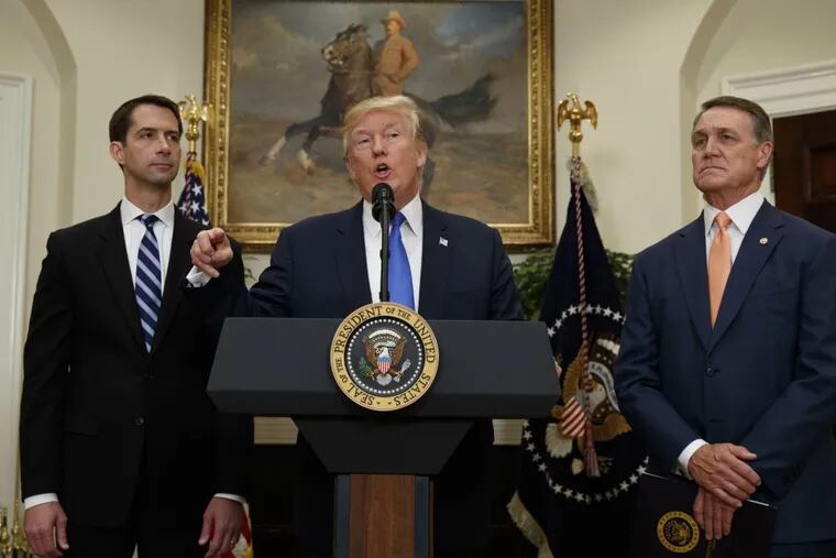 Sens. Tom Cotton (left)  and David Perdue look on as President Trump speaks during the unveiling of the RAISE Act.