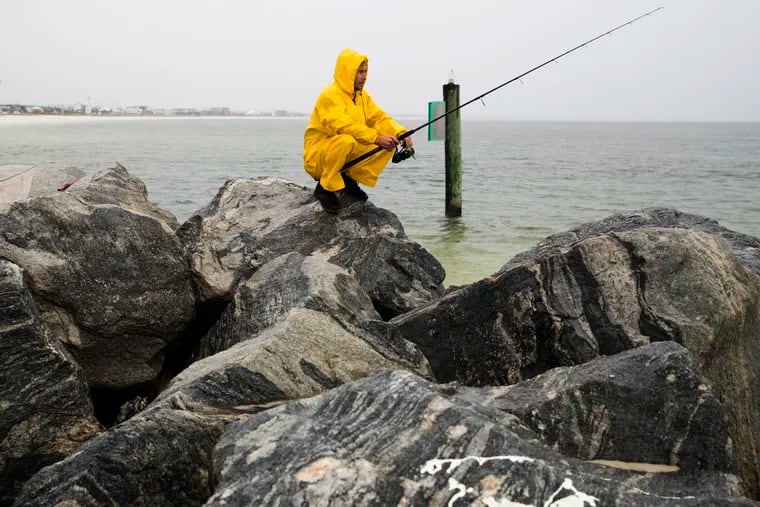 Michael Foster fishes as Tropical Storm Nestor approaches, Friday, Oct. 18, 2019 in Mexico Beach, Fla.. Forecasters say a disturbance moving through the Gulf of Mexico has become Tropical Storm Nestor.