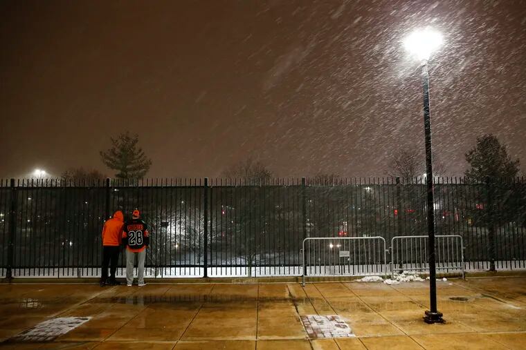 Flyers fans wait to catch a glimpse of a Flyers player as snow falls at the Wells Fargo Center in South Philadelphia Monday night.