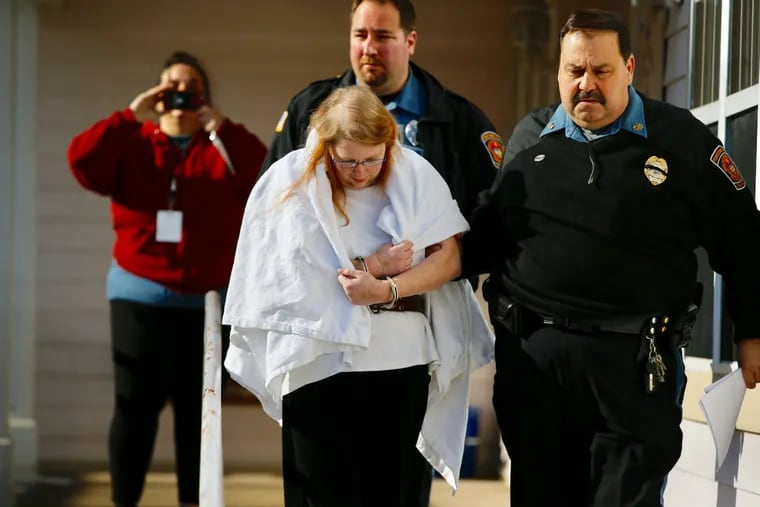 Sara Packer, center in white, is lead out of District Court in Newtown, PA on Sunday afternoon after being charged with several counts in the murder of her 14-year-old adopted daughter Grace Packer.
