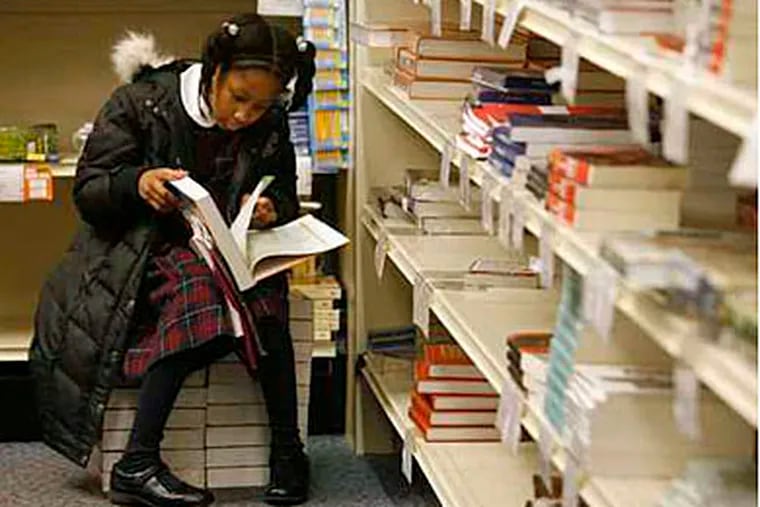 While visiting the Penn State Abington bookstore, third grader Devia Terry checks out an algebra textbook.