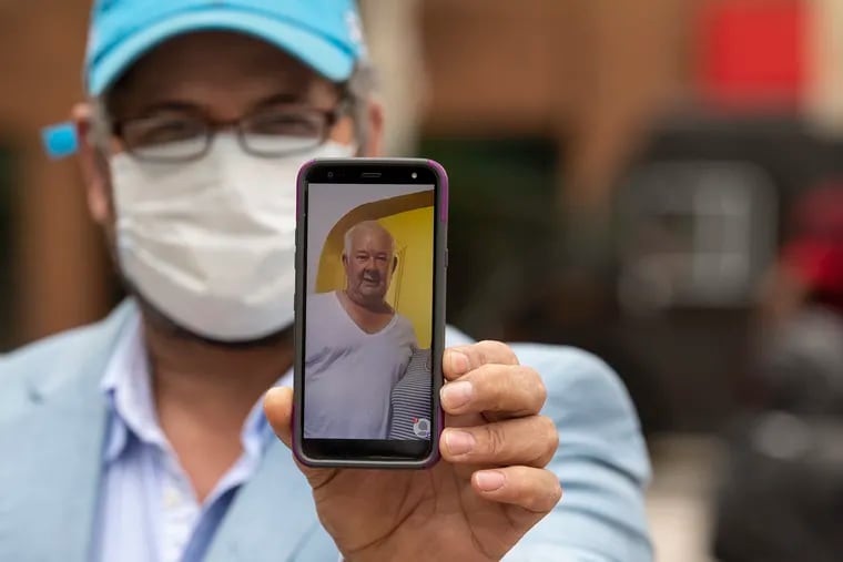 Rafael Ferreiras shows an iPhone photo of his late father, also named Rafael, who died of COVID-19. The wife of the elder Ferreiras works at the Bell & Evans poultry processing plant in Fredericksburg, Pa.