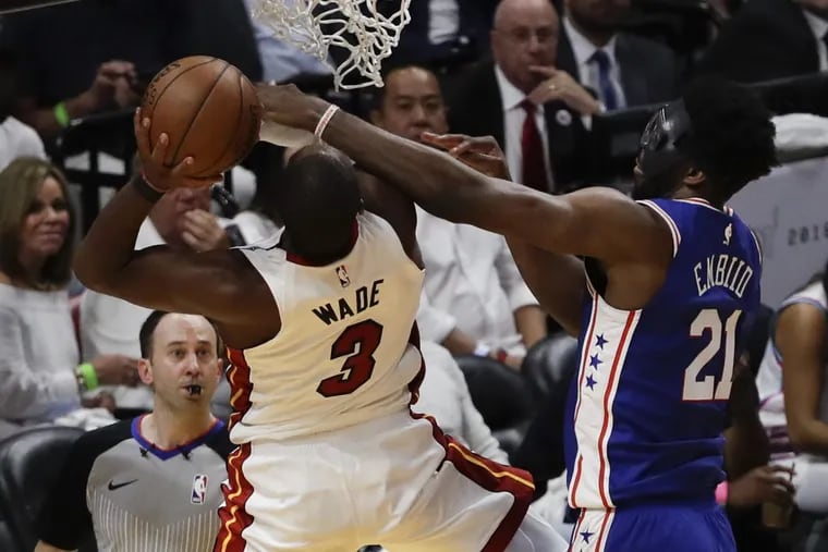 Sixers center Joel Embiid fouls Miami Heat guard Dwyane Wade during the first-quarter in game three of the Eastern Conference quarterfinals on Thursday, April 19, 2018 in Miami.