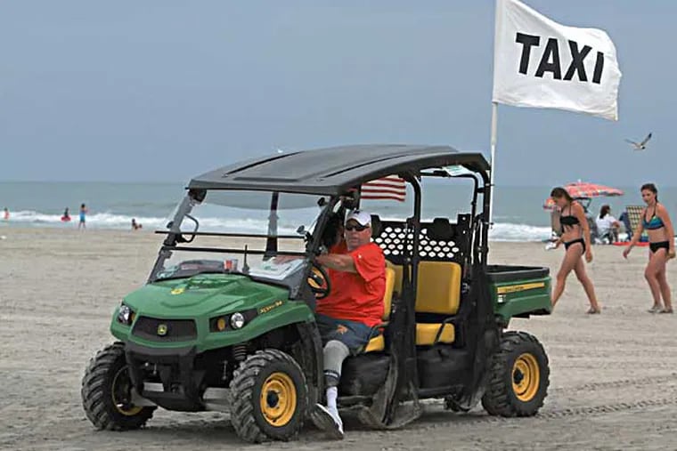 In Wildwood City, beach officials test their hands at a new program, beach taxi service. Beachgoers can now avoid the cumbersome walk to the water, at points, a quarter-mile hike, for a small fee.  Jim Kenny waits in a John Deer Gator on the beach looking for customers on July 24, 2014.    ( CHARLES FOX / Staff Photographer )