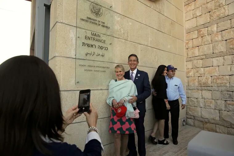 FILE - In this May 14, 2018 file photo, visitors have a photo taken at the entrance to the new U.S. Embassy in Jerusalem. The U.S. said Thursday Oct. 18, 2018 that it is placing its main diplomatic mission to the Palestinians under the authority of its embassy to Israel. The State Department said Thursday that merging the Jerusalem Consulate with the newly opened Jerusalem Embassy will achieve "significant efficiencies." But the move also has symbolic significance, by in effect downgrading the standing of the consulate. (AP Photo/Sebastian Scheiner, File)