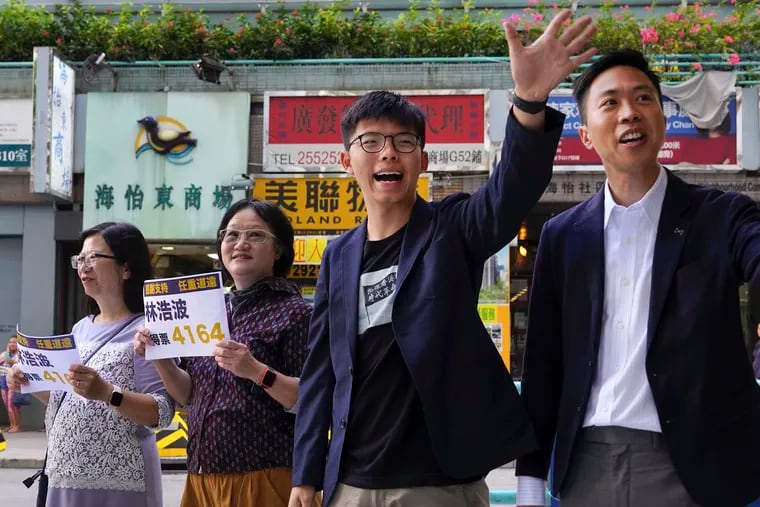Kelvin Lam (right), an election winner, and pro-democracy activist Joshua Wong (second from right), thank supporters outside South Horizons Station in Hong Kong on Monday. Pro-democracy candidates won nearly half of the seats in Hong Kong's local elections, according to partial returns Monday, as voters sent a clear signal of support for the anti-government protests that rocked the Chinese territory for more than five months.