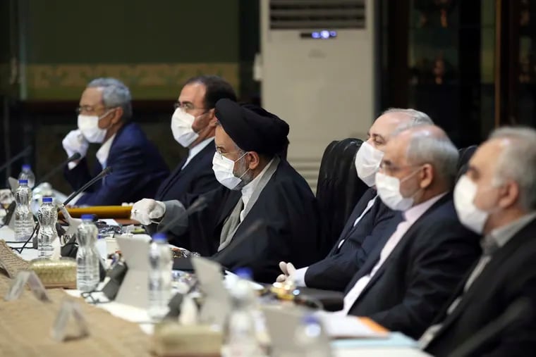 In this photo released by the official website of the Office of the Iranian Presidency, cabinet members wearing face masks and gloves attend their meeting in Tehran, Iran.